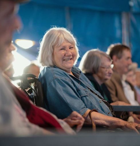 Seniorin im Publikum lächelt bei einer Veranstaltung